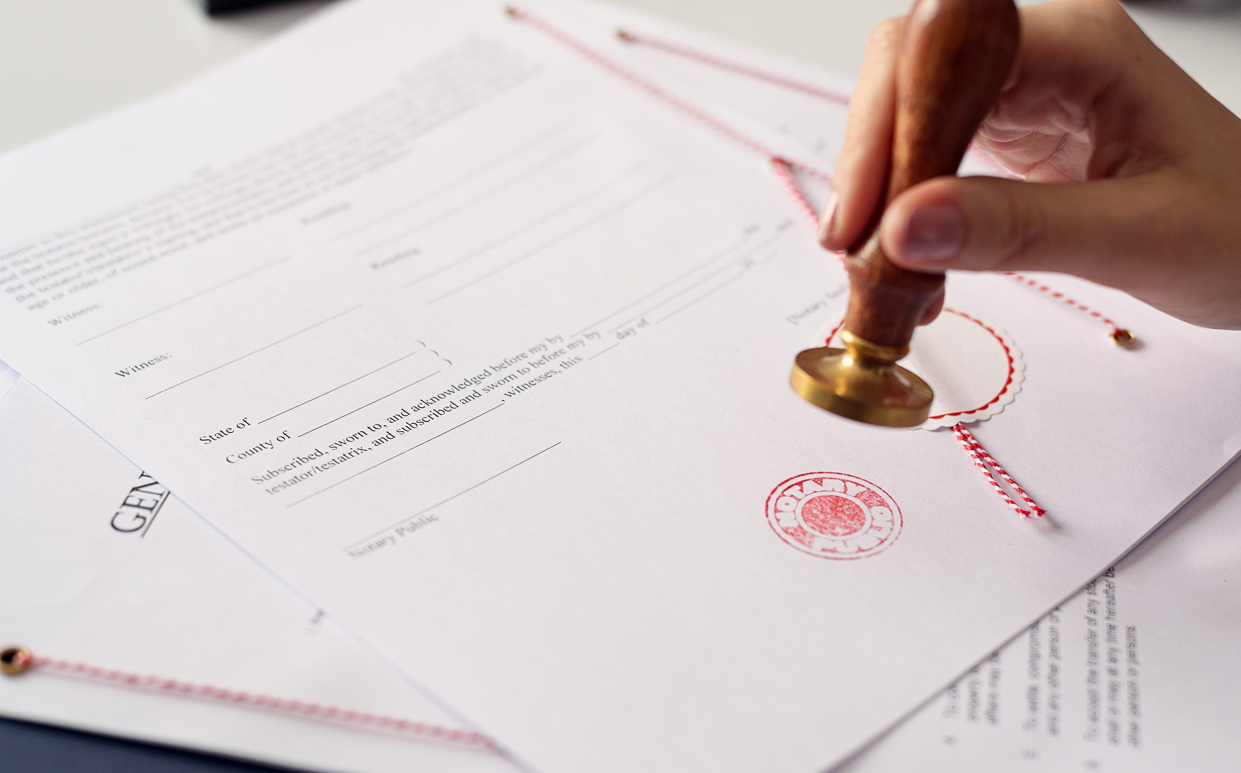 A hand stamping a red notary stamp on a document.