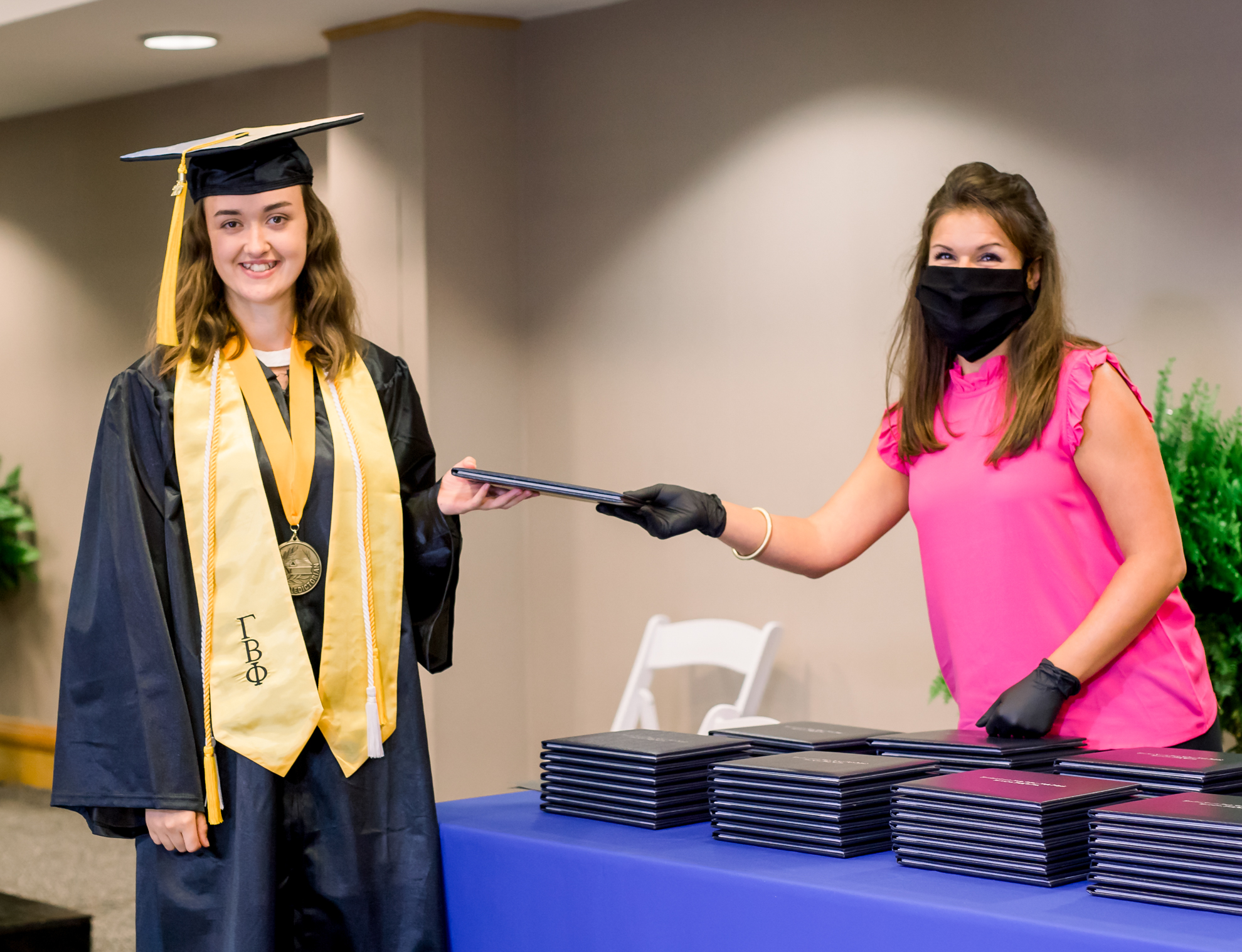 A person in graduation gear accepts a diploma