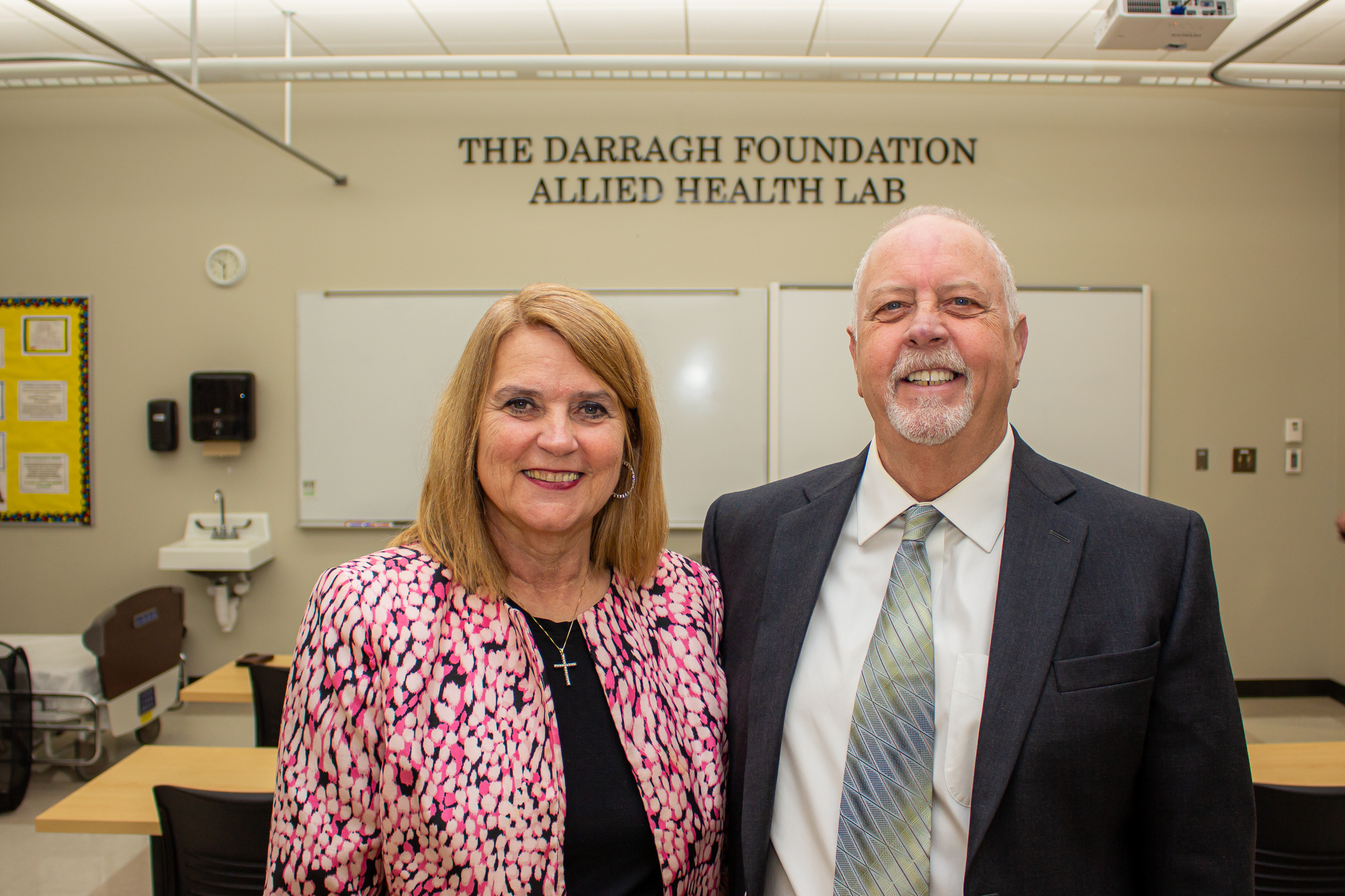 two people in front of sign reading The Darragh Foundation Allied Health Lab