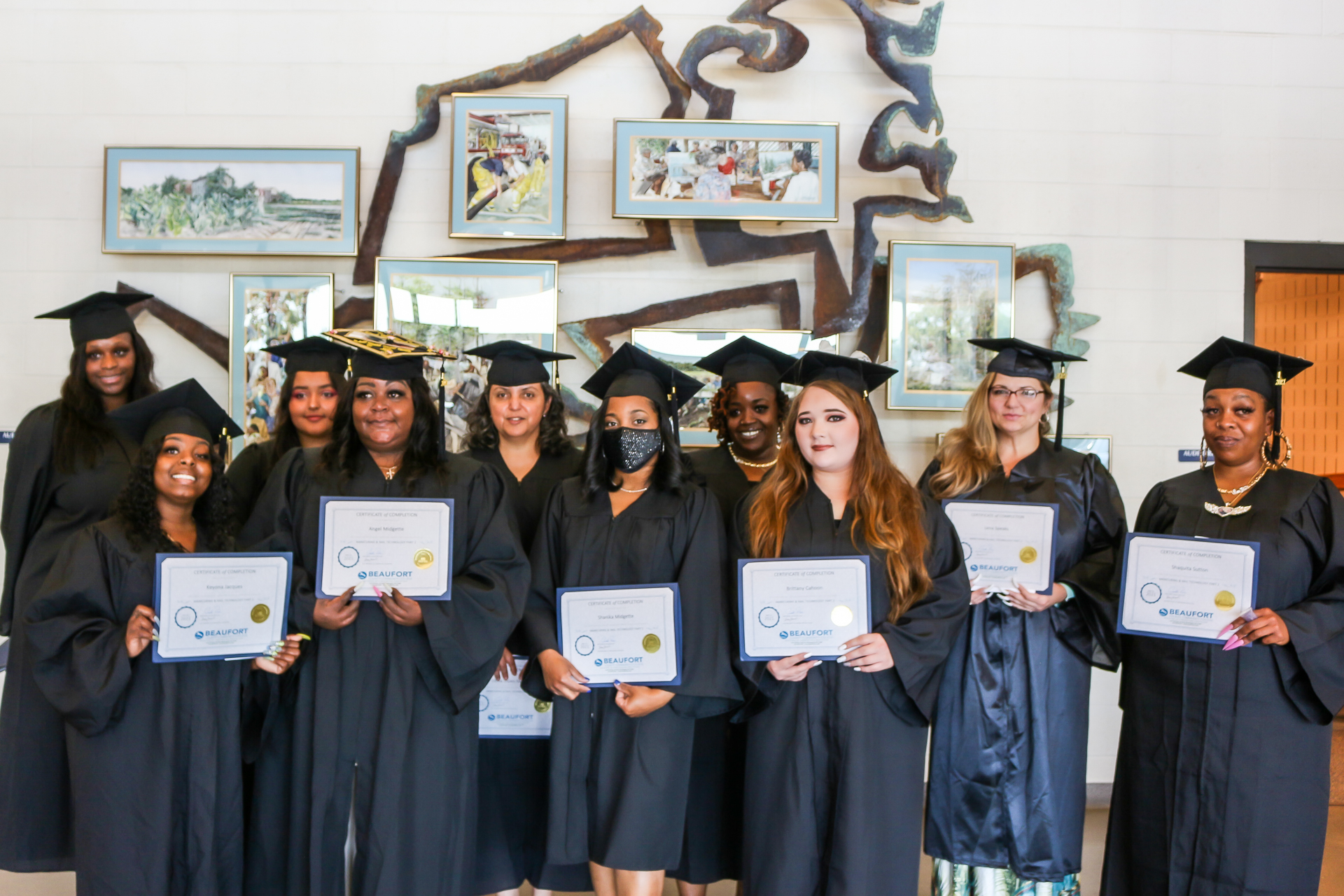 Students with certificates in caps and gowns